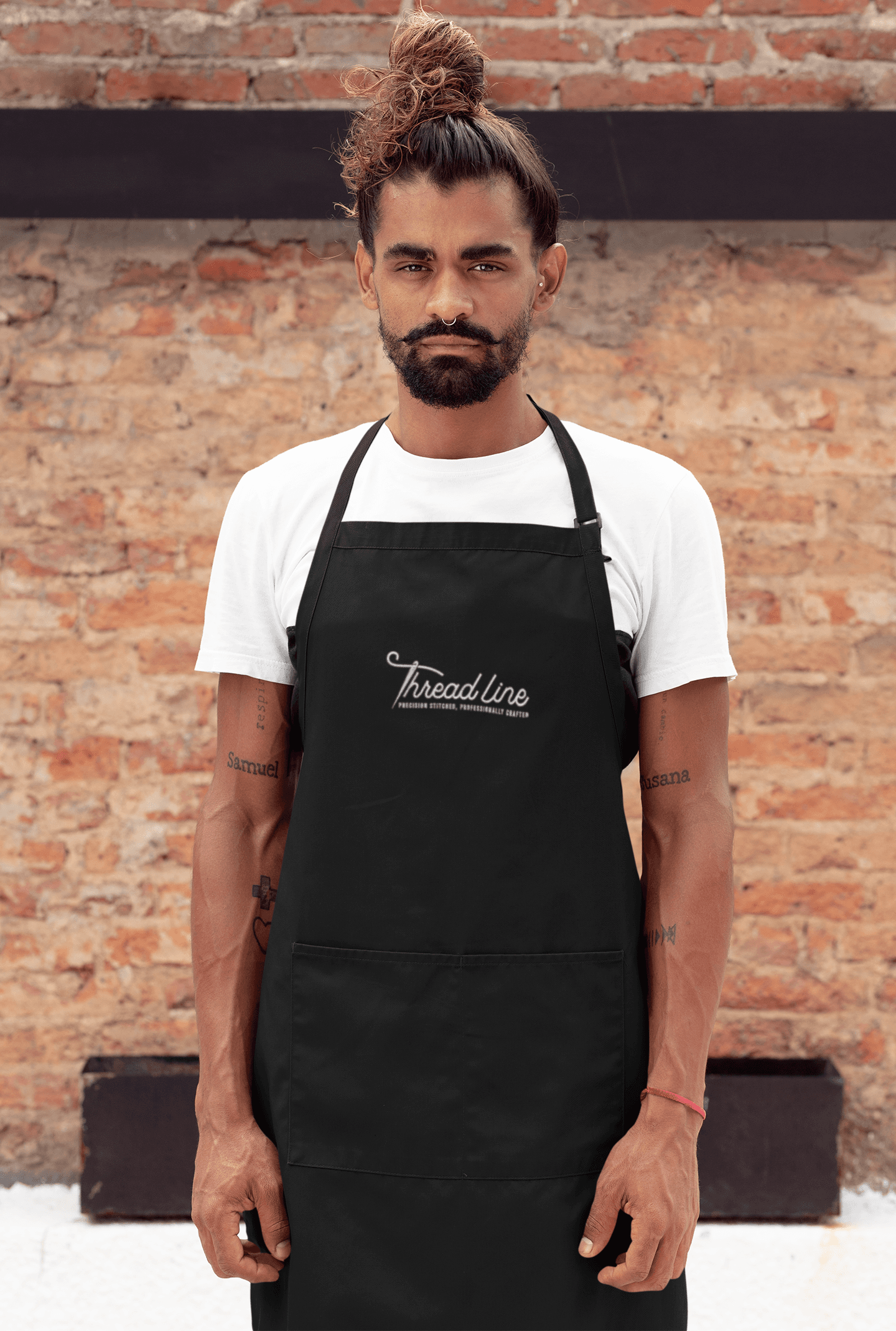 Staff member wearing a black apron with an embroidered chest logo