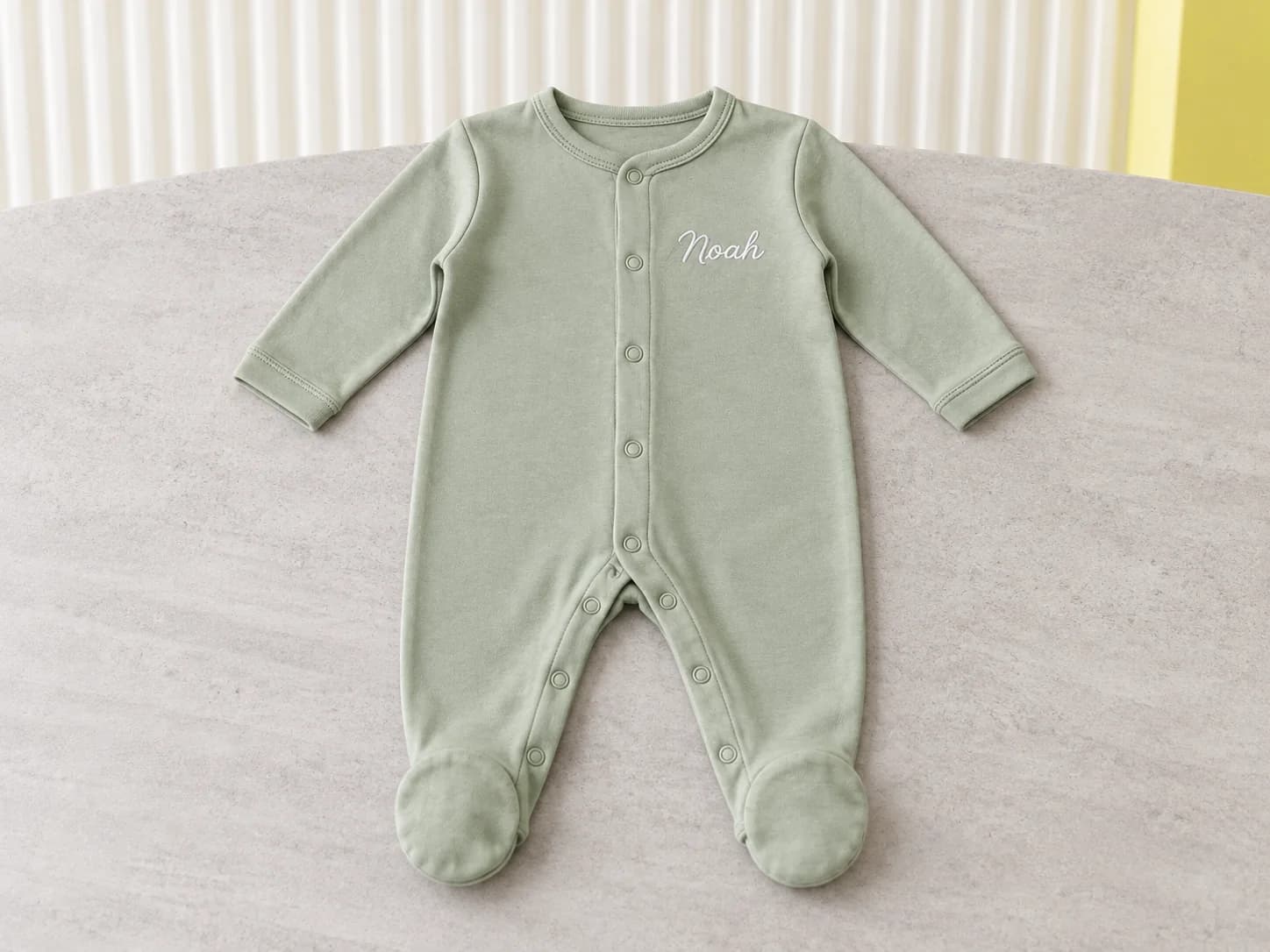 Sage footed baby sleepsuit embroidered with the name Noah