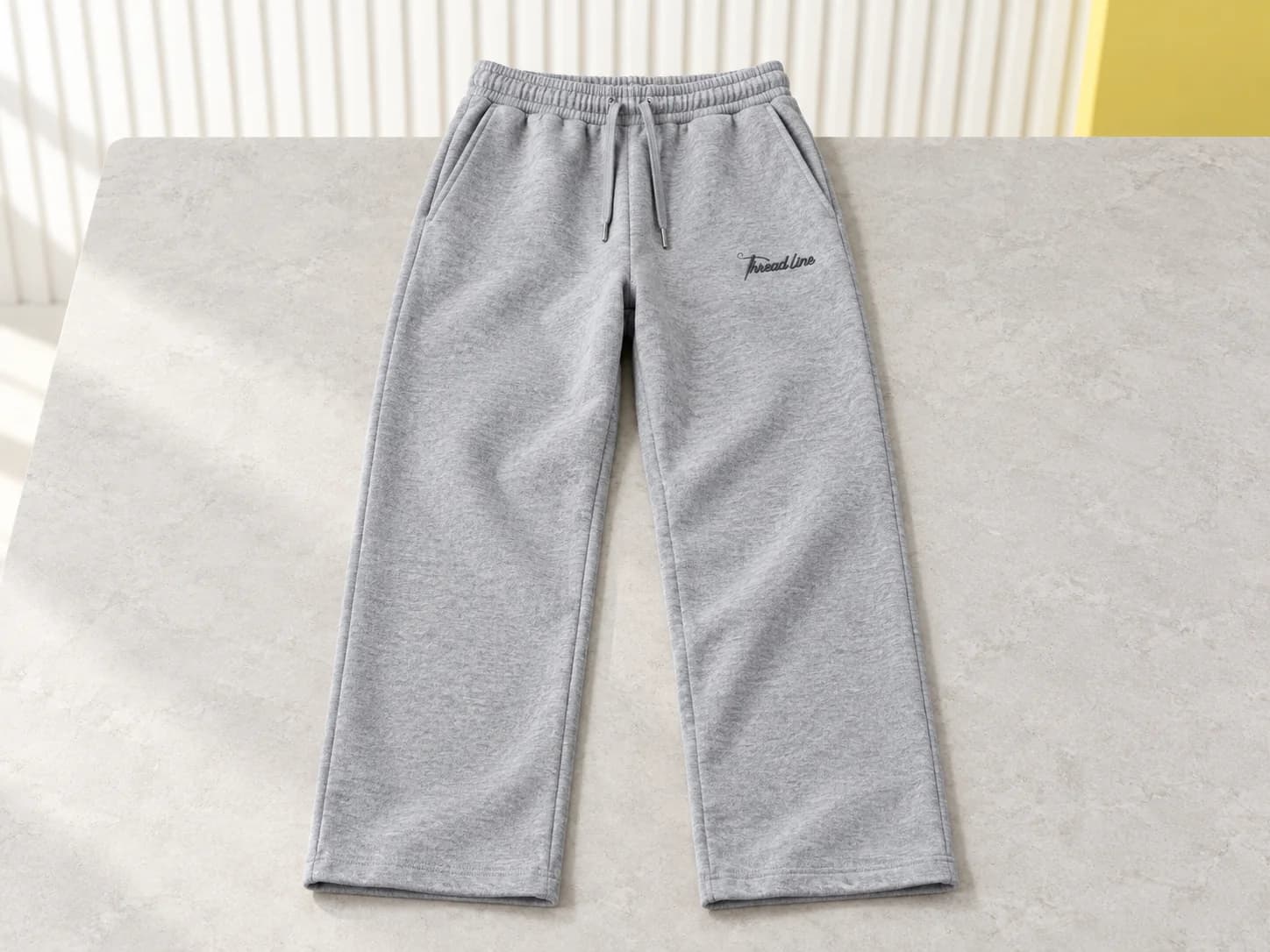 Grey straight-leg sweatpants with small charcoal Threadline thigh embroidery