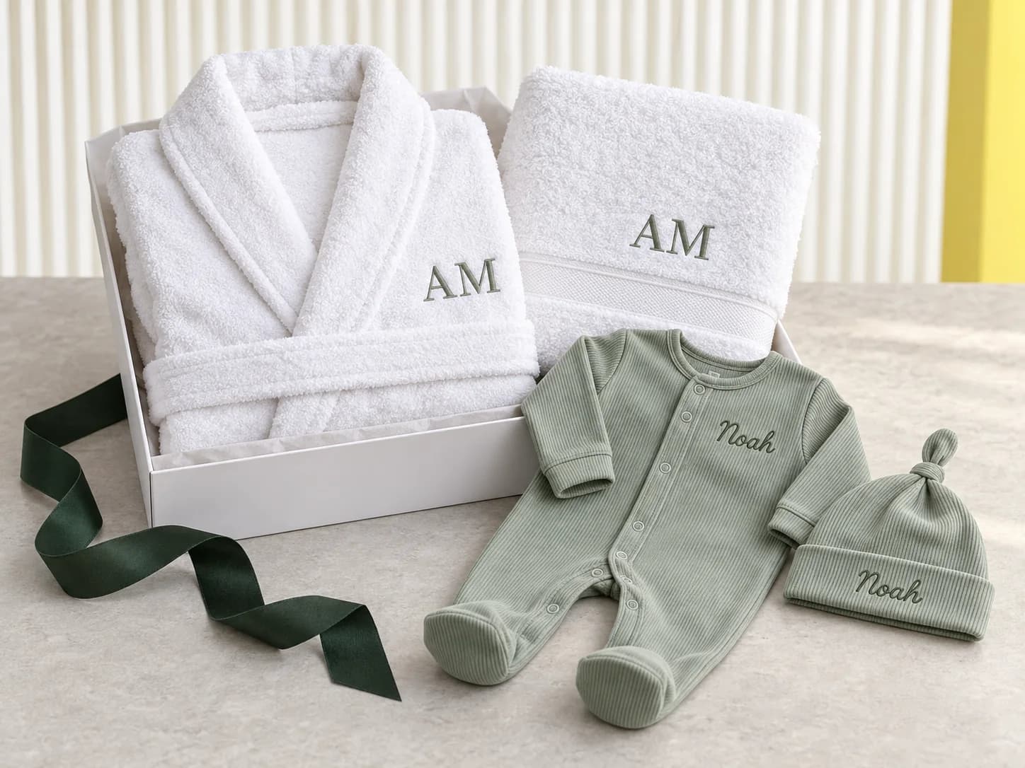 Coordinated embroidered robe, towel, baby sleepsuit and hat presented as gift ideas